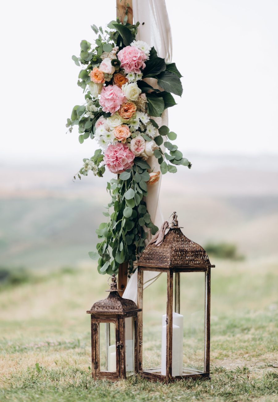 Floral composition made of eucalyptus and tender pink flowers and candles outdoors